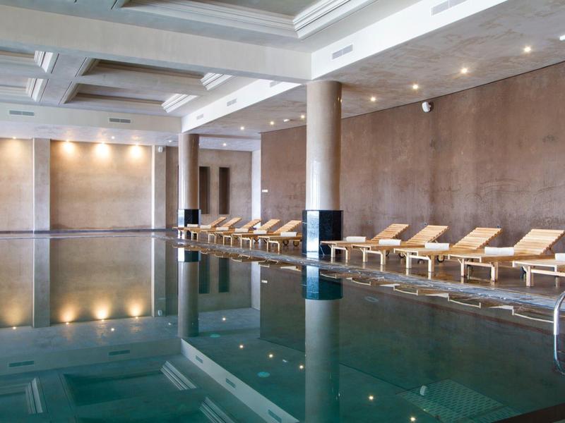 Moderne binnenzwembad met ligstoelen en zachte verlichting in een ontspannen sfeer.