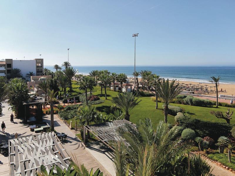 Park met palmbomen en groene gebieden naast strand en zee onder een heldere lucht