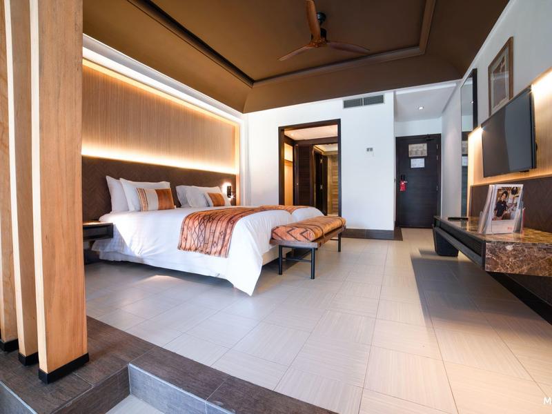 Moderne hotelkamer met groot bed, indirecte verlichting en houten kamerverdelers.