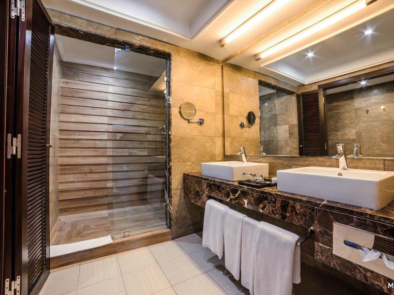 Elegant badkamer met zwarte marmeren voorkant, twee wasbakken en een glazen douche.