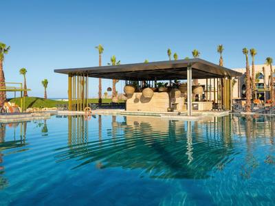 Moderner Poolbereich mit Bar und Palmen unter klarem Himmel