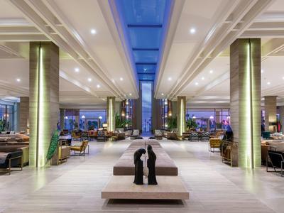 Weitläufige Hotellobby mit hohen Säulen, moderner Beleuchtung und gemütlichen Sitzbereichen.