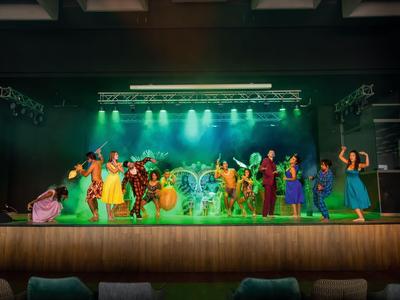 Bunte Theateraufführung mit vielen Schauspielern und grüner Bühnenbeleuchtung