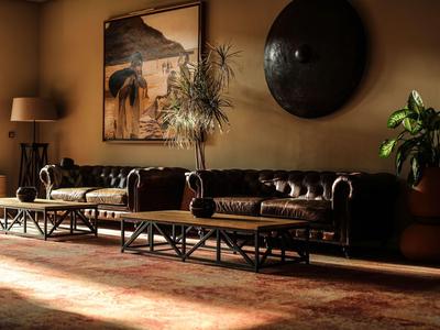 Cozy living room with brown leather sofas, plants, and wall art.