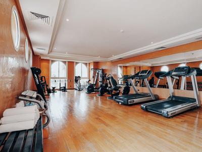Brightly lit gym with treadmills and exercise equipment on wooden floor