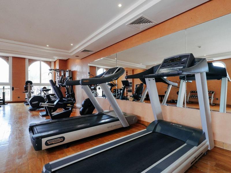 Moderner Fitnessraum mit Laufbändern, Fahrrädern und großen Spiegeln an der Wand.