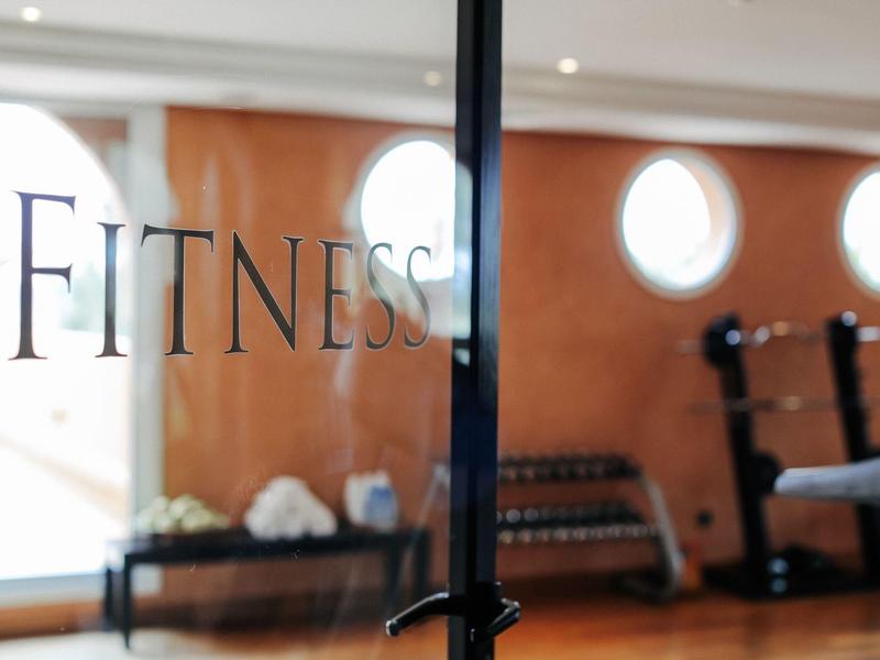 Schwarzer Metallstab in Nahaufnahme mit durchsichtiger Glaswand und Fitnessbereich im Hintergrund.