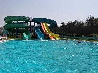 Zjeżdżalnia wodna z wieloma kolorowymi torami obok odkrytego basenu