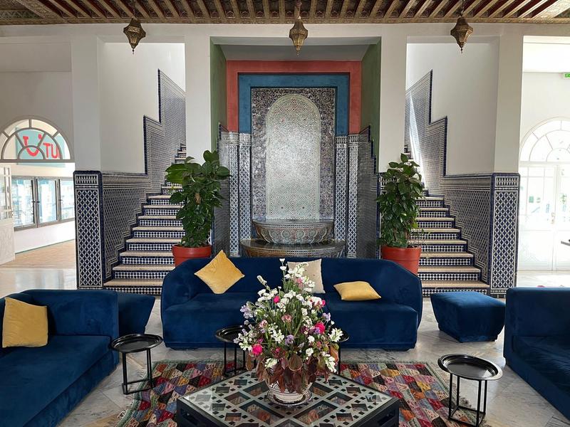 Przytulny salon z niebieskimi siedzeniami, kwiatową dekoracją i schodami po obu stronach w hotelu.