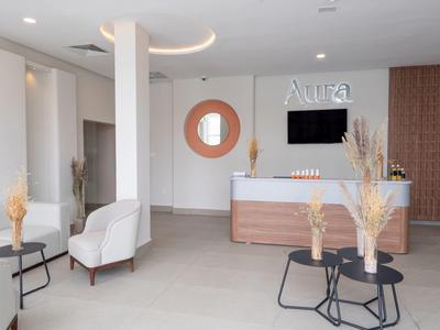 Moderne Hotel-Lobby mit braunem Empfangstresen, weißen Sesseln und dekorativen Tischen.