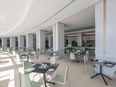 Área de comedor luminosa y moderna con sillas y mesas blancas en un hotel.