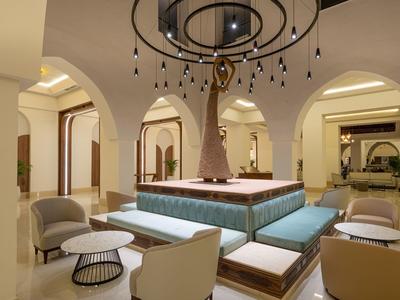 Área de salón de hotel elegante con asientos cómodos alrededor de una estatua central.