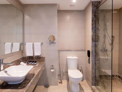 Modernes Hotelbad mit Waschbecken auf Marmorplatte, Toilette und Glaskabine für Dusche.