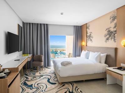 Modernes Hotelzimmer mit großem Bett, Meerblick und stilvoller Inneneinrichtung.