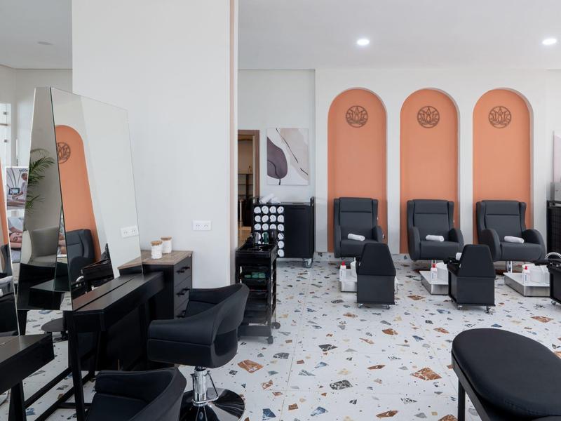 Moderne Friseursalon mit schwarzen Stühlen, orangen Rückwänden und Mosaikfliesenboden.