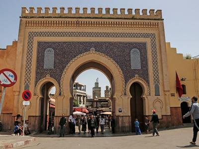 Historisches maghrebinisches Stadttor mit Menschen und modernen Verkehrsschildern davor
