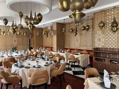 Elegant dining room with round tables, black chairs, and gold hanging lamps.