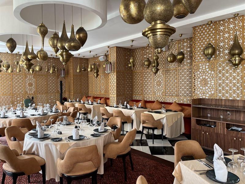 Elegantes Restaurant mit runden Tischen, bequemen Stühlen und dekorativen Hängelampen.