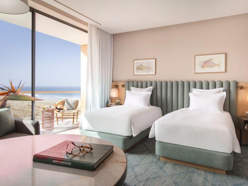 Moderne hotelkamer met twee eenpersoonsbedden, balkon met zeezicht en stijlvolle inrichting.