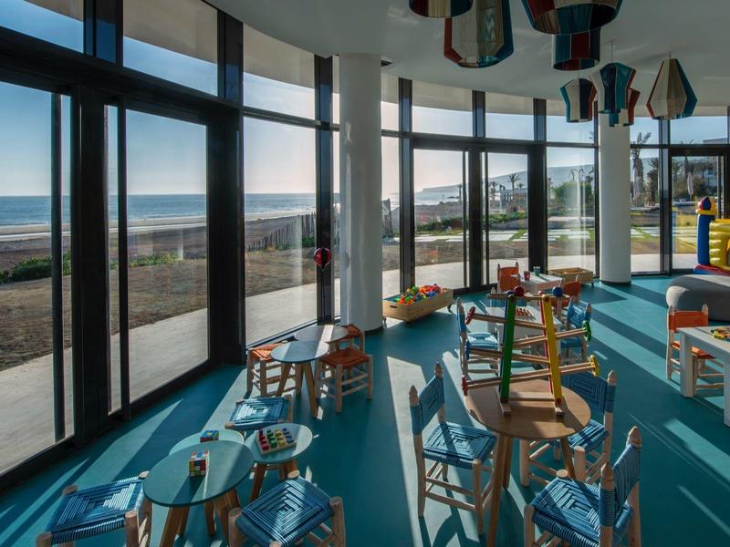 Interieur met grote panoramische ramen en een speelruimte voor kinderen met uitzicht op zee.