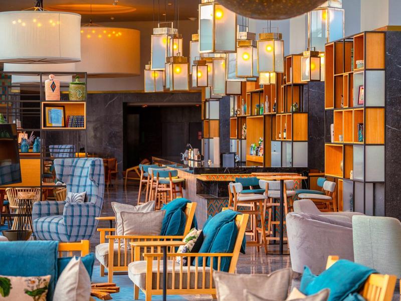 Moderne hotelbar met comfortabele fauteuils, houten meubels en sfeerverlichting.