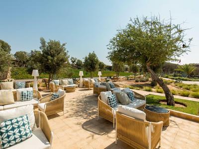 Outdoor area with cozy seating and decorative cushions in a hotel garden.