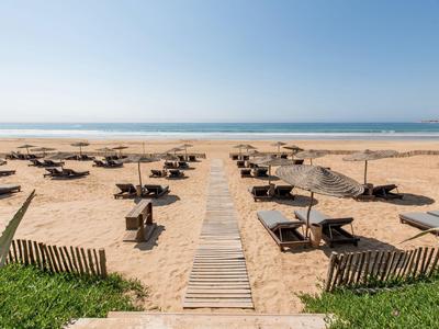 Sandy beach with wooden path and sun umbrellas in a sunny seaside resort