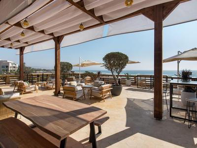 Covered outdoor terrace with seating areas and sea view in sunny weather.