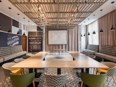 Large conference room with square wooden table, projection screen, and modern seating.