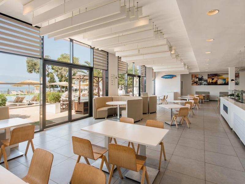 Salle à manger lumineuse et moderne avec grandes fenêtres et vue sur la mer.