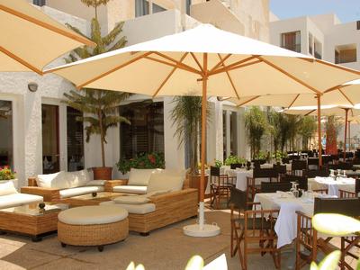 Strefa zewnętrzna hotelu z parasolami, krzesłami i stołami pod czystym niebem.