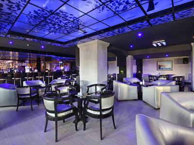 Moderne Hotelbar mit Lounge-Möbeln und stimmungsvoller blauer Beleuchtung.