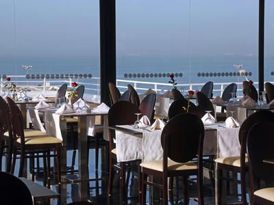 Elegantes Restaurant mit festlich gedeckten Tischen und Meerblick durch große Fenster.