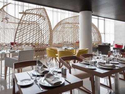 Moderní restaurace se stylovými dřevěnými a proutěnými židlemi a elegantně prostřenými stoly.