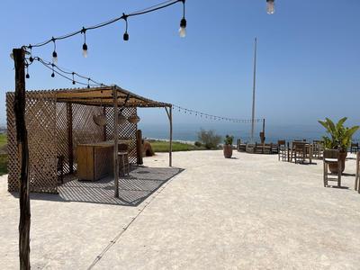 Velká terasa s dlážděnou podlahou, posezením a výhledem na moře pod jasnou oblohou.