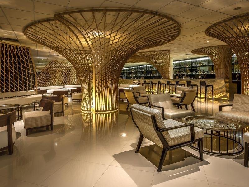 Elegante Hotel-Lobby mit goldener Säulendekoration, bequemen Sesseln und warmem Licht.