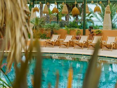 Un'area piscina tranquilla con sdraio e piante tropicali in un hotel.