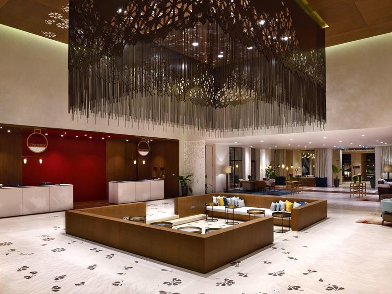 Luxury hotel lobby with large seating island and striking chandelier on the ceiling