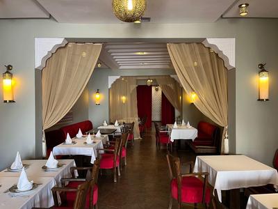 Elegantes Restaurant mit weißen Tischdecken, roten Stühlen und warmem Licht.