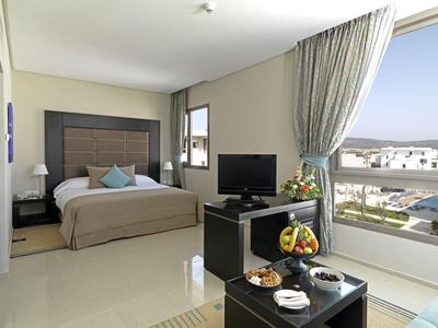 Modernes Hotelzimmer mit großem Bett, TV und Panoramafenster mit Stadtblick.