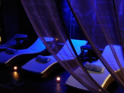 Trzy leżaki z poduszkami i światłem świec w ciemnym, nastrojowym spa.