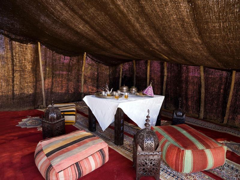 Przytulny kącik z dywanami, poduszkami i latarniami pod namiotem.