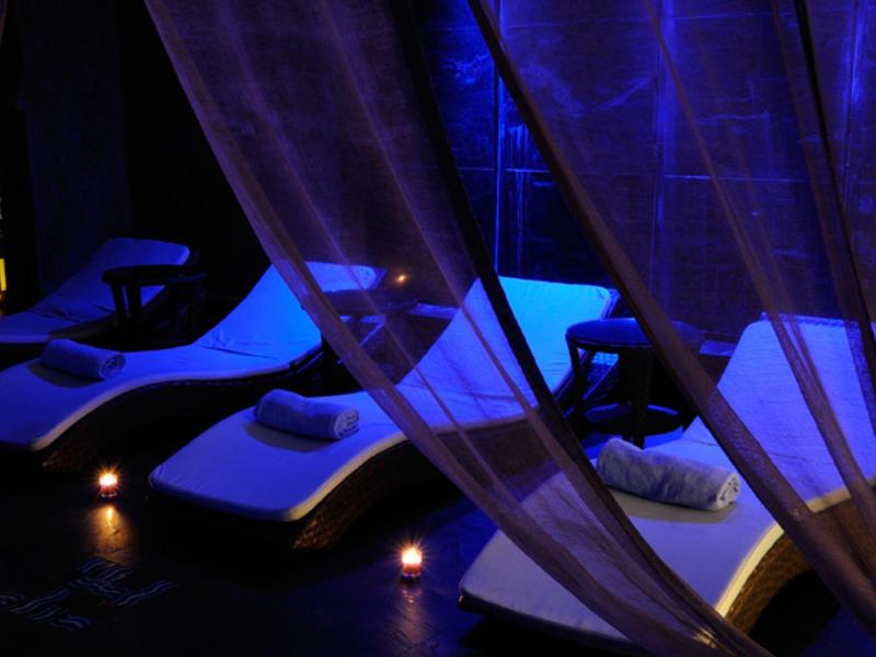 Trzy leżaki z poduszkami i światłem świec w ciemnym, nastrojowym spa.