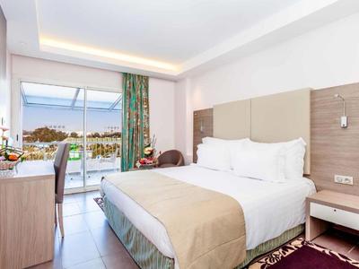 Bright hotel room with large bed, terrace, and sea view.