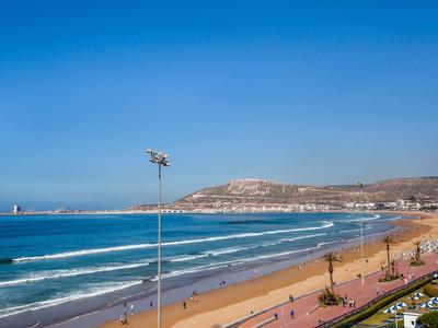 Wide sandy beach with promenade beside blue sea and clear sky