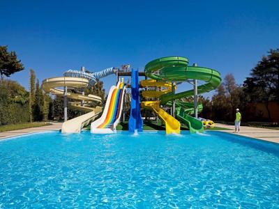 Colorful water slide park with clear pool and blue sky in a hotel leisure area.