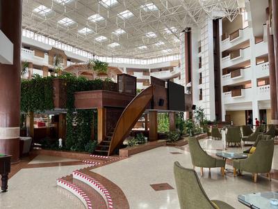Large hotel lobby area with modern architecture, plants, and seating areas.
