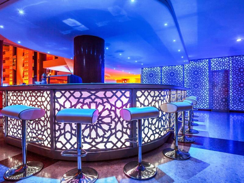 Moderne bar met verlichte balie en hoge krukken in blauwe en paarse tinten.