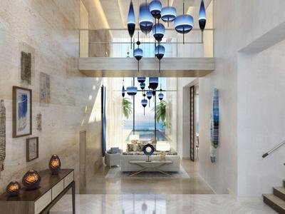 Modernes, helles Hotelfoyer mit blauen Hängelampen und weitem Blick nach draußen.