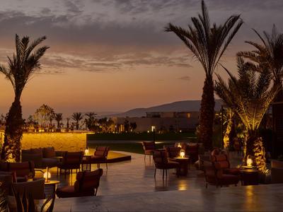 Abendliche Szene einer Terrasse mit Palmen und warmem Licht in einem Hotelgarten.